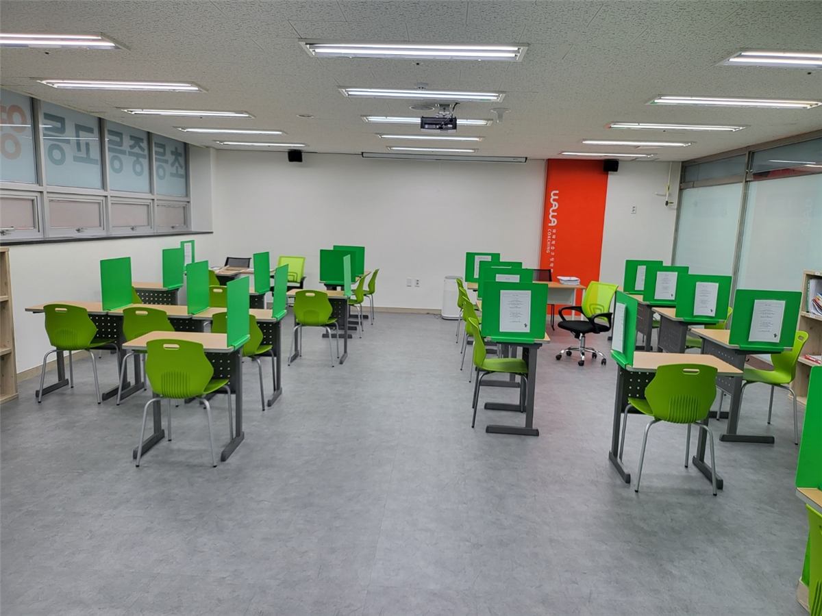 와와학습코칭 대구장기점 코칭 교실 — 초록색 가림판이 세워진 개인 책상들 사이에 선생님용 책상과 의자가 함께 놓여 있는 모습